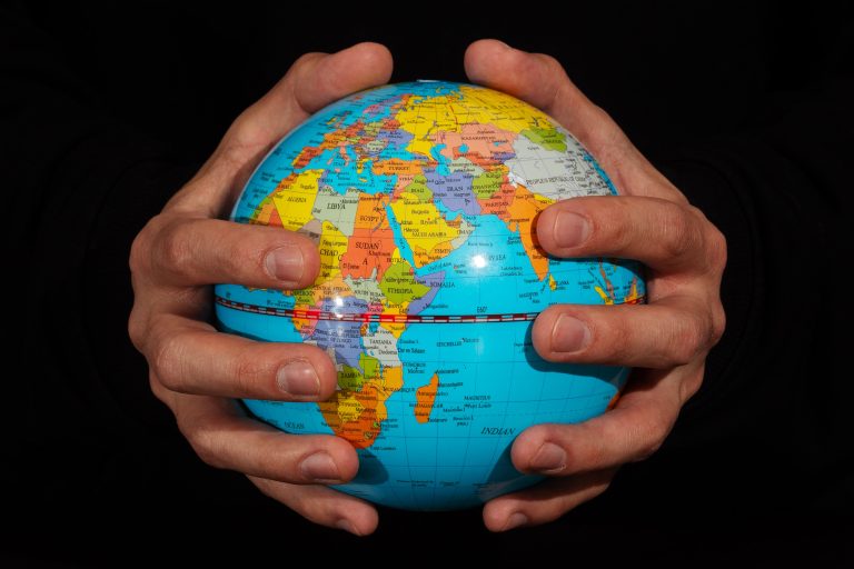 Macro,Photo,Of,A,Male,Hands,Holding,A,Political,Map