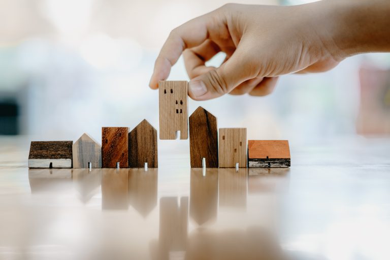 Hand,Choosing,Mini,Wood,House,Model,From,Model,And,Row