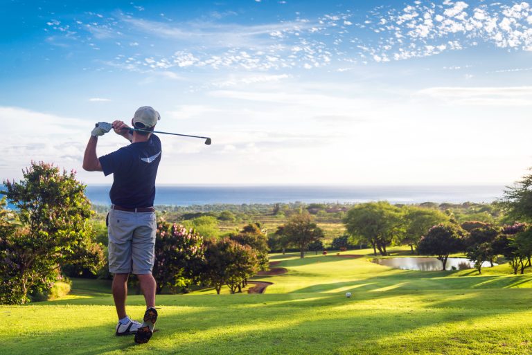 Man,Hitting,Golf,Ball,Down,Hill,Towards,Ocean,And,Horizon